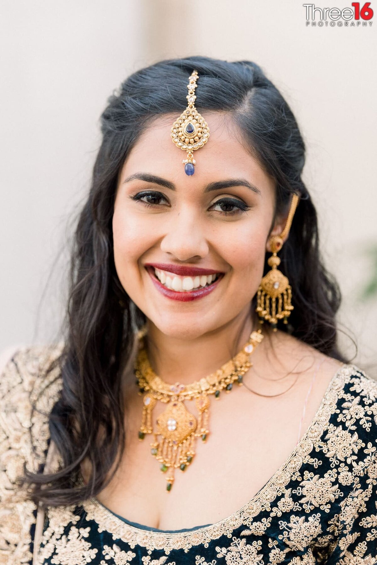 Decked out in a traditional Indian head dress Bride flashes a big smile for the wedding photographer