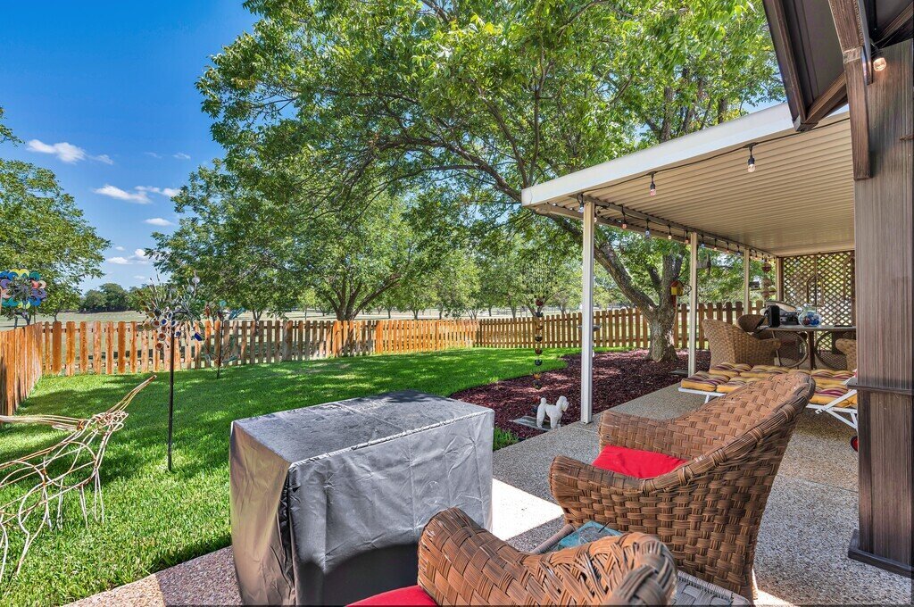 Covered patio lounge and spacious backyard area at this three-bedroom, two-bathroom vacation rental home with hot tub, firepit, and free WiFi just minutes from Lake Waco.