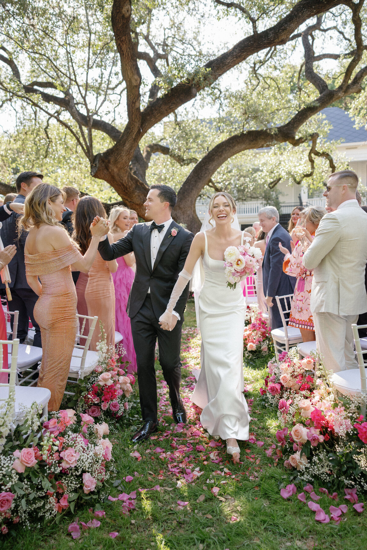 bride and groom recessing at wedding reception outdoors with pink florals