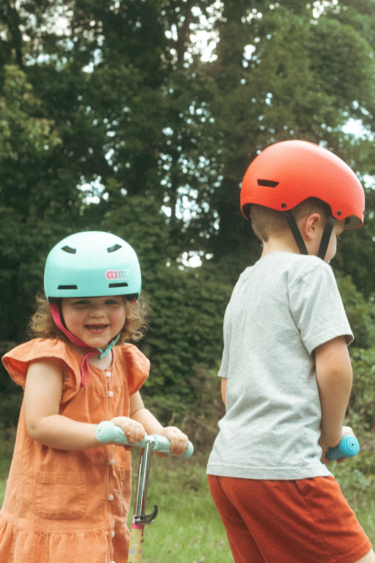 Two kids in bright colored helmets riding scooters at Noonday Creek Trail. 