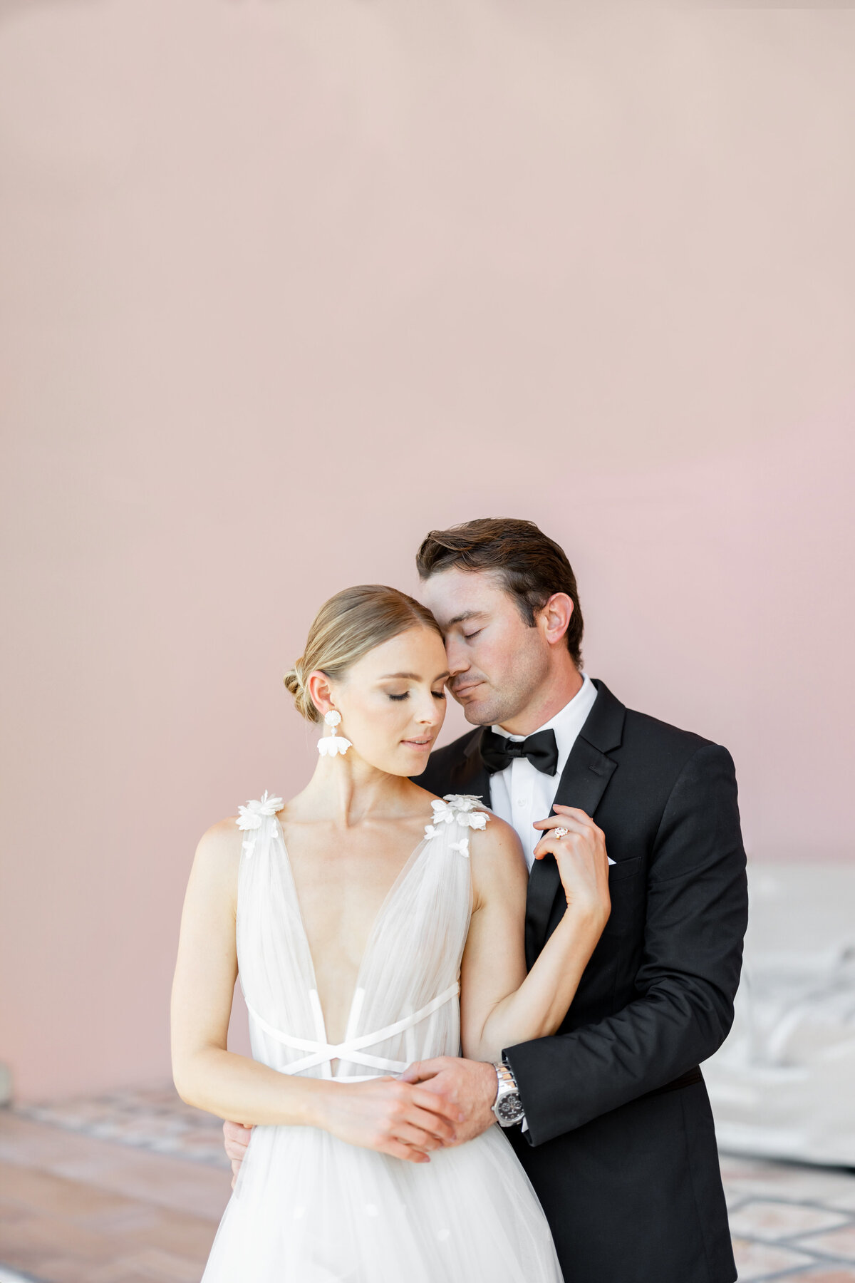 bride and groom leaning against each other with pink background by wedding photographers florida