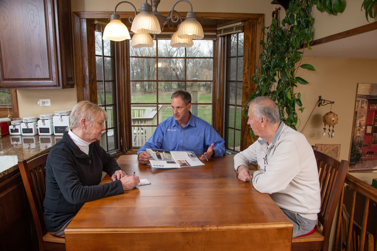 Three men are sitting at a table in front of a window