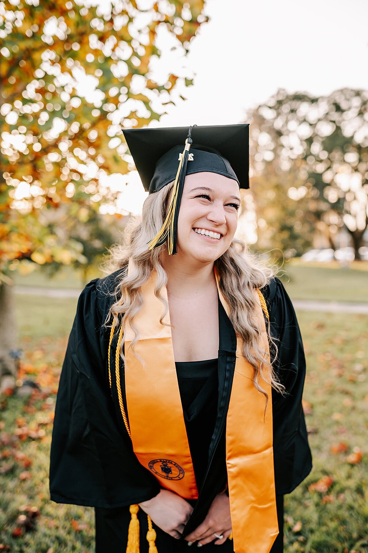 Nursing student in cap and gown laughing during a graduation session in Winter park