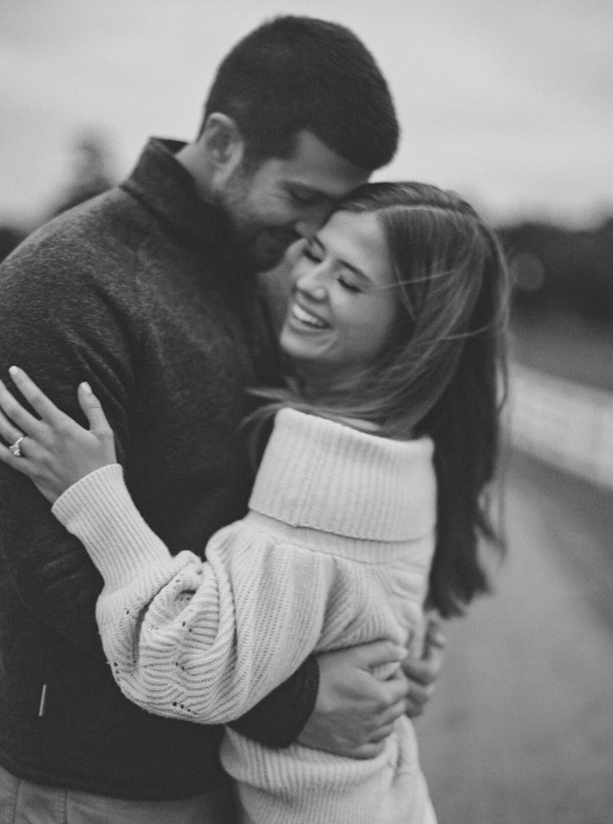 engaged couple smile as they stand forehead to forehead