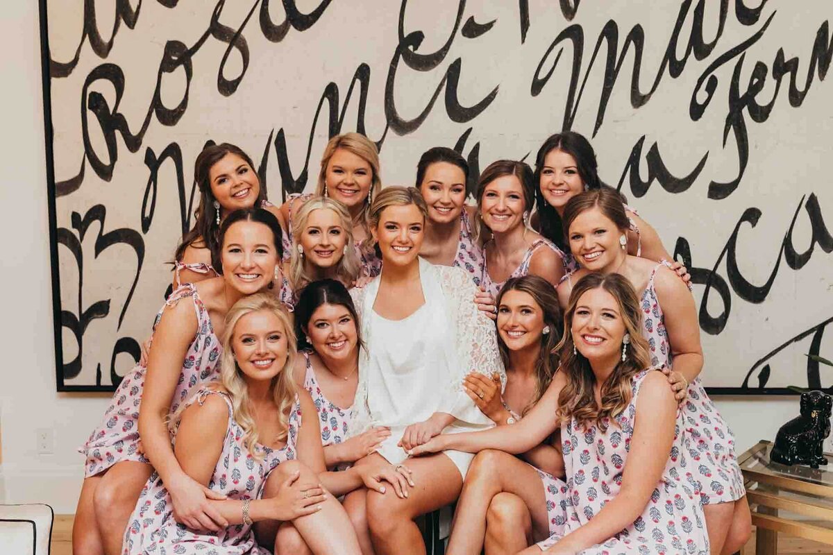 bridal party surrounds bride on her special day, against a black and white large painting.