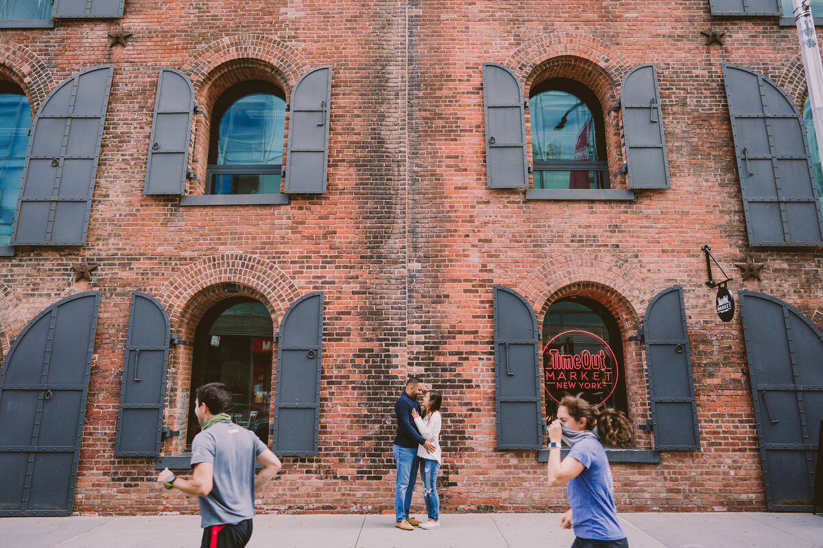 A couple standing in front of the timeout market in brooklyn dumbo nyc