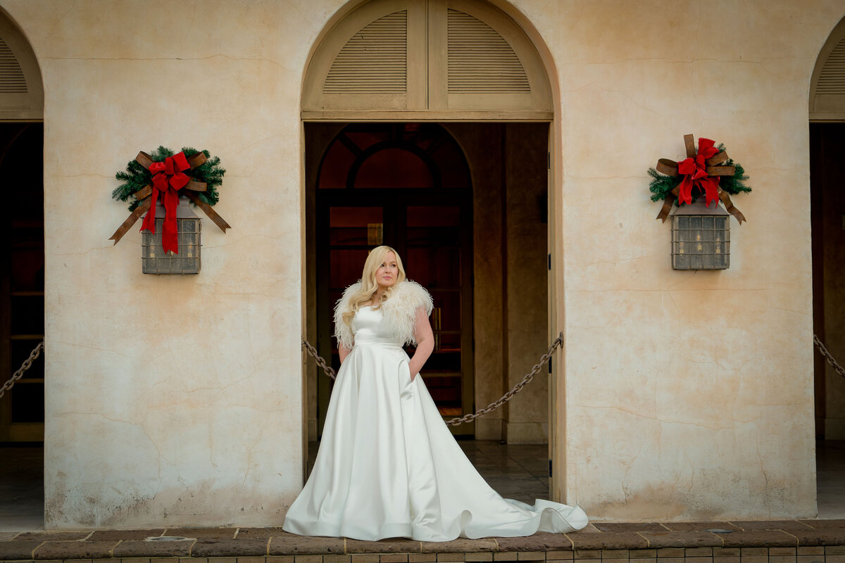 Beautiful bride poses for portrait in front of arched doorway