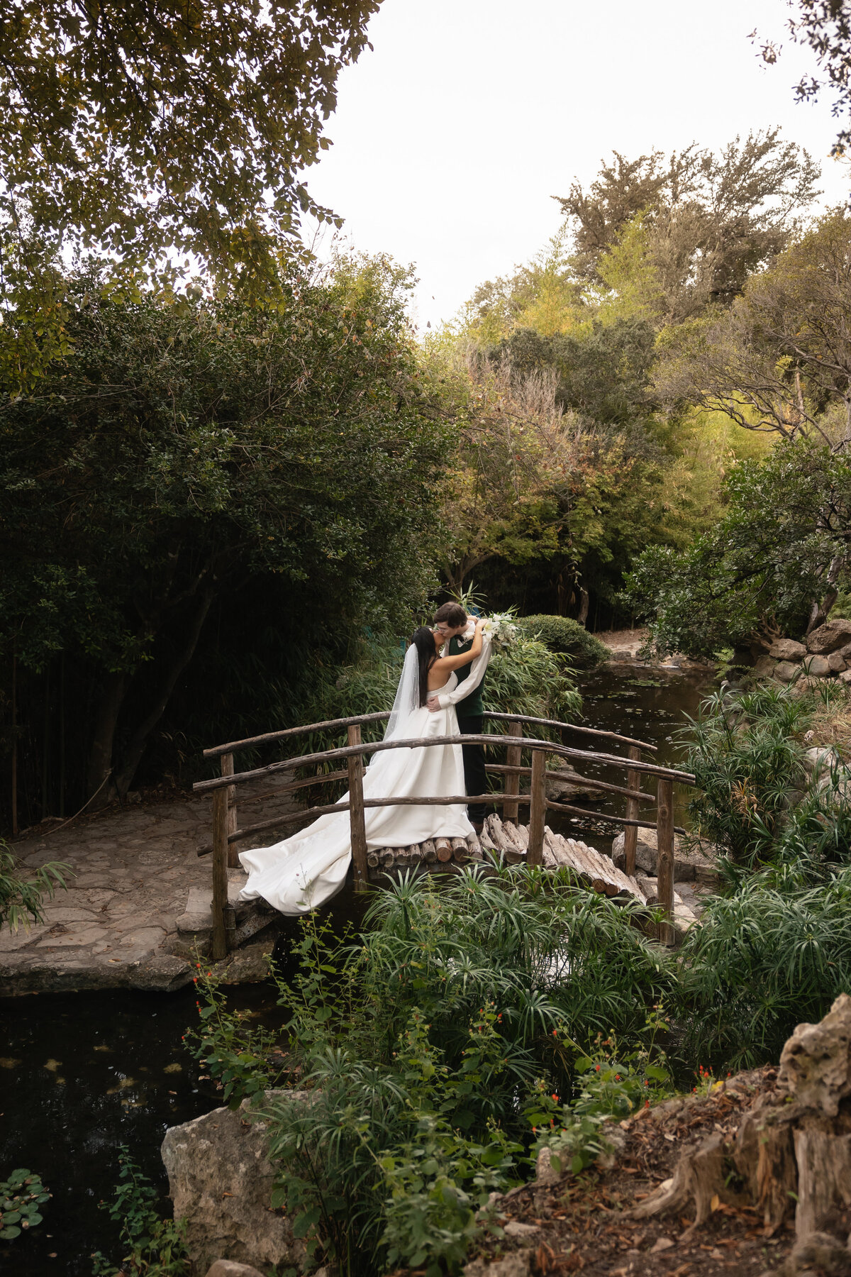 wedding photographer takes photo of bride and groom on a bridge