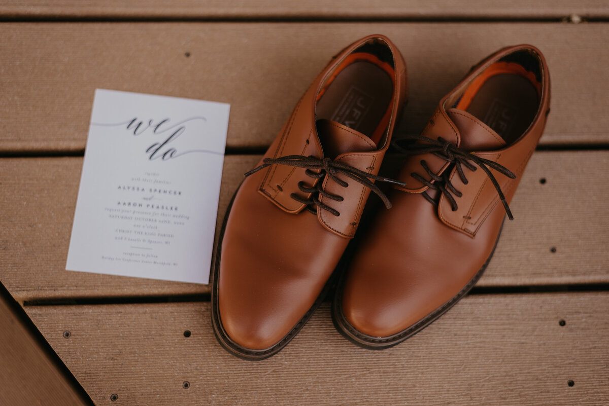 Groom's wedding shoes photographed next to invitation.