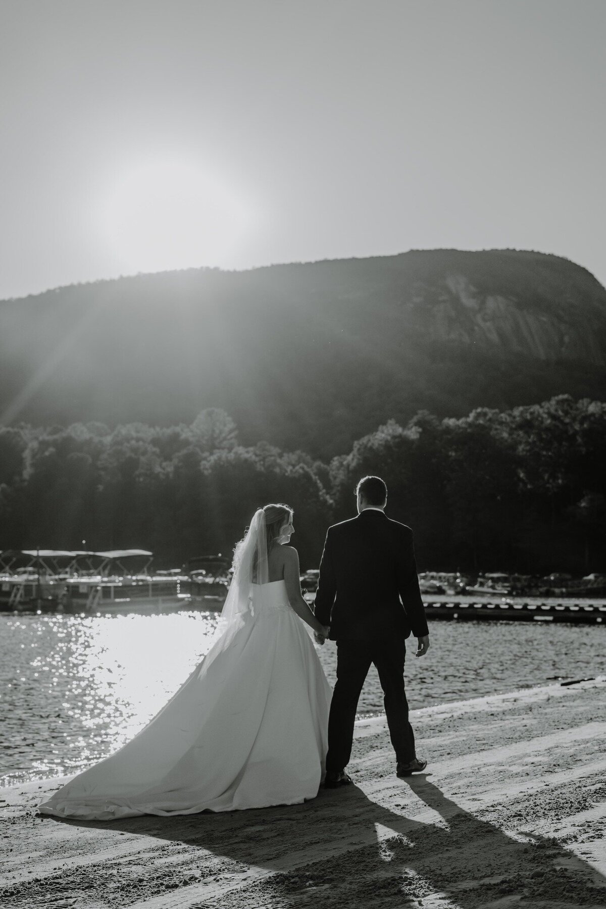 newly married couple walking along the beach at the rumbling bald at lake lure