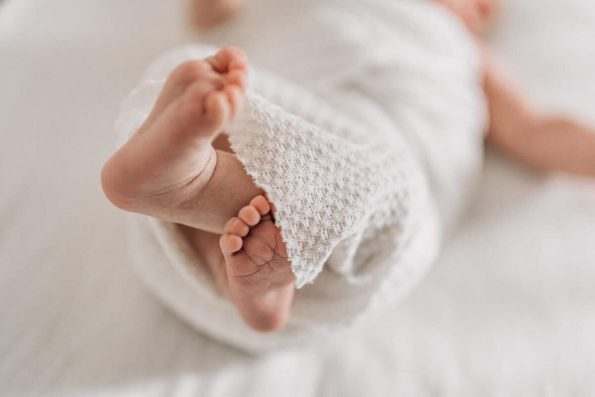 A close up image of baby's toes in focus, while the rest of the baby fades out of focus.