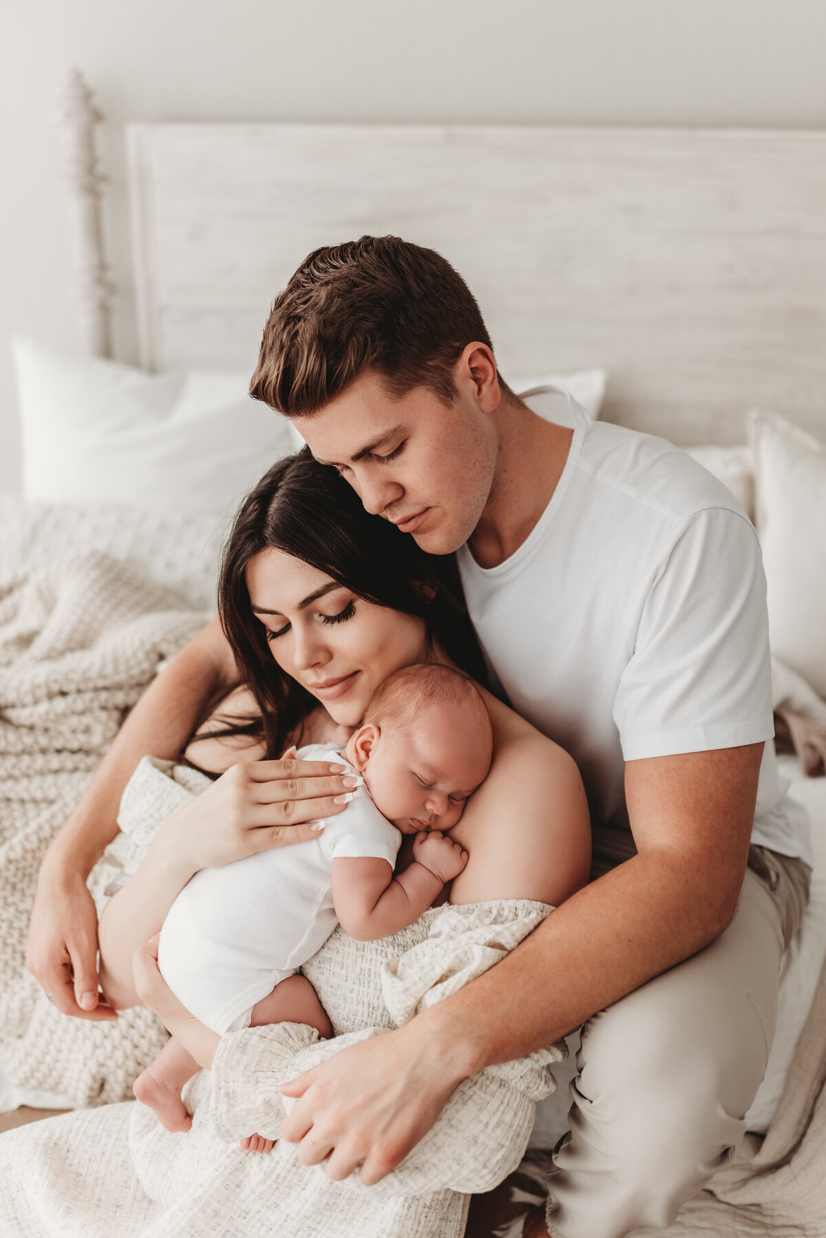 mom and dad snuggling baby in newborn photographer studio