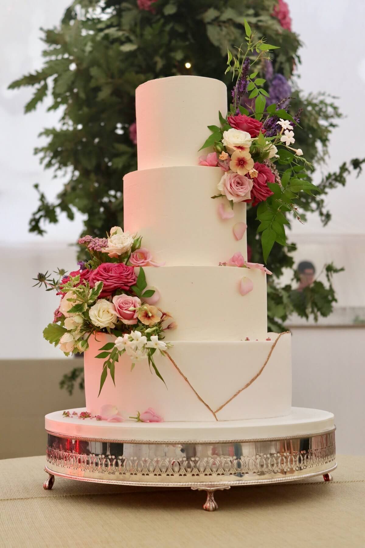A 4 tier wedding cake with two clusters of flowers