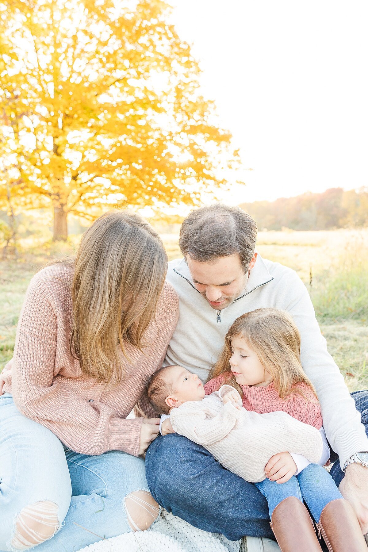 family sits together during outdoor newborn photo session with Sara Sniderman Photography