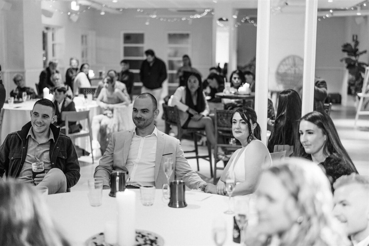 Hannah & Cory sitting on a table listening to their speakers at the wedding reception