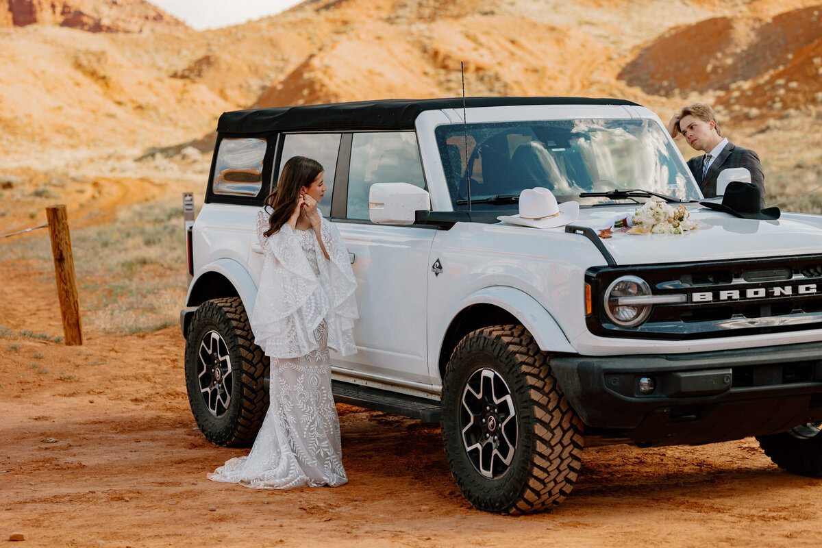 A bride and groom use their car windows as mirrors as they get ready for their elopement. 