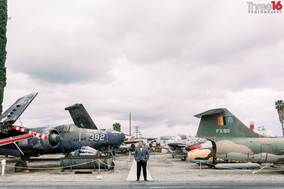 Groom poses in front of an array of vintage planes at the Planes of Fame Air Museum