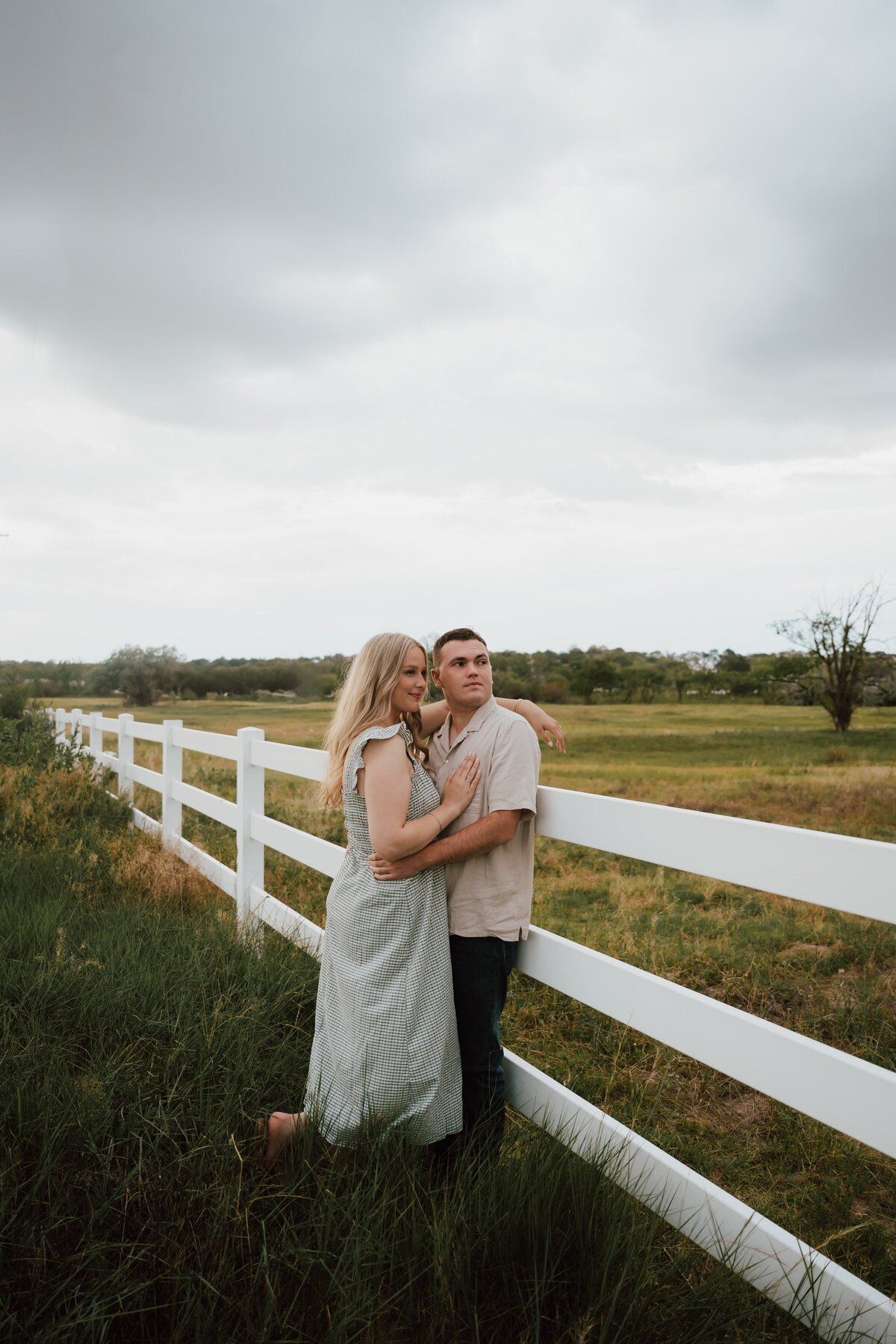 engaged-couple-standing-with-fence