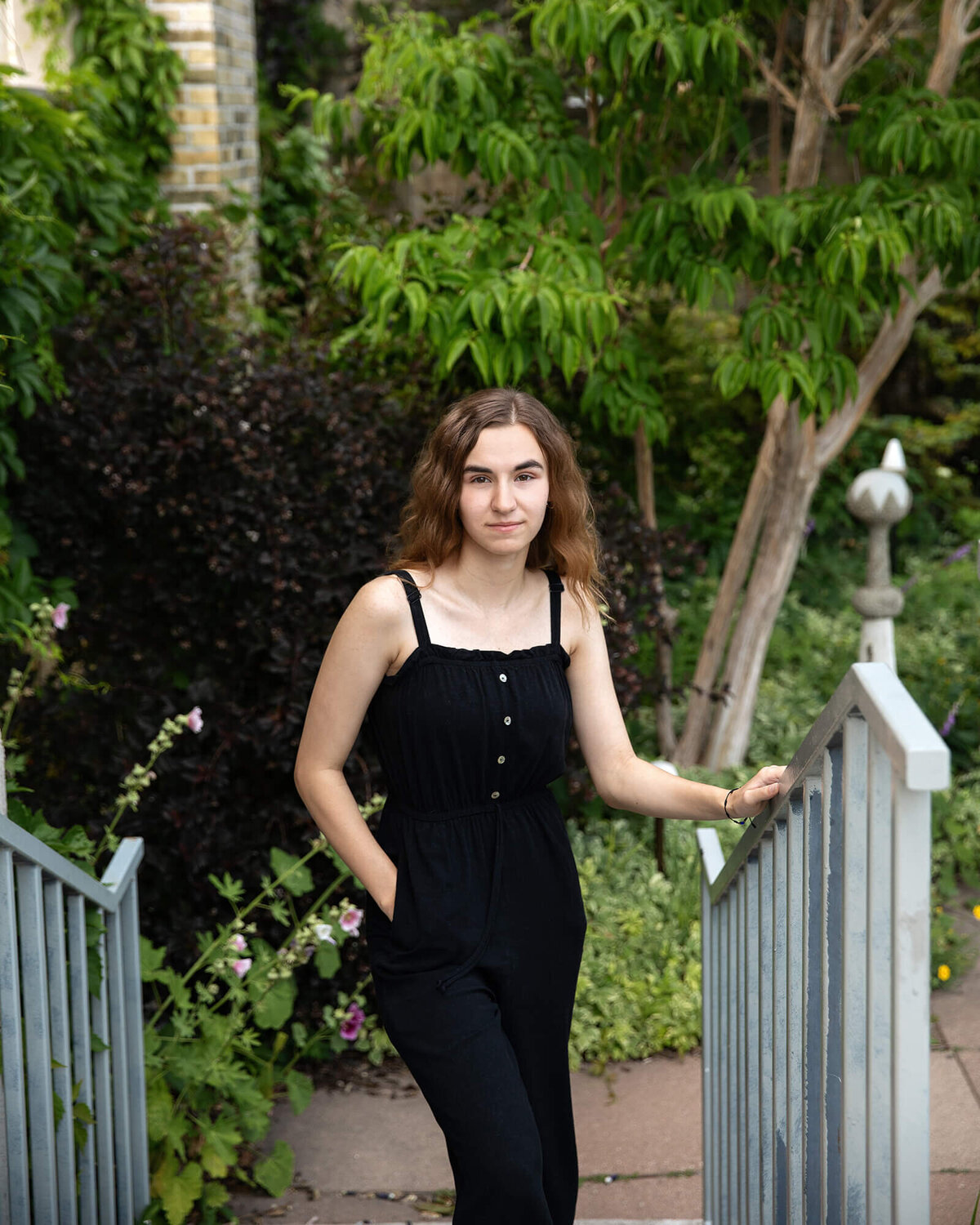 Senior girl standing at the bottom of stairs in a garden.