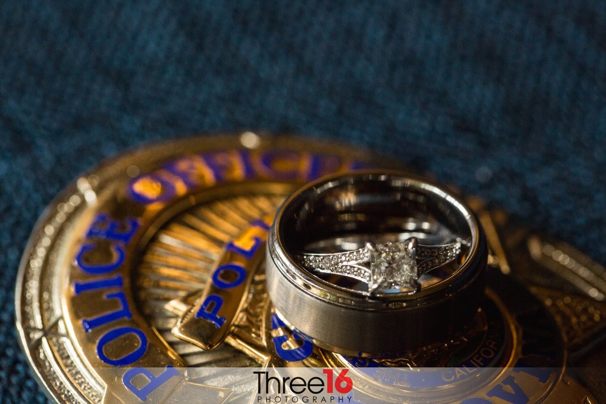 Bride and Groom's wedding rings sit together on top of their police badge