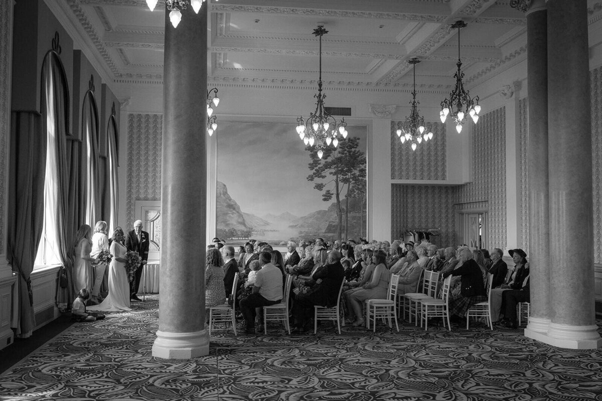 The Balmoral Edinburgh set up for a wedding with a room full of guests engaged in the wedding service