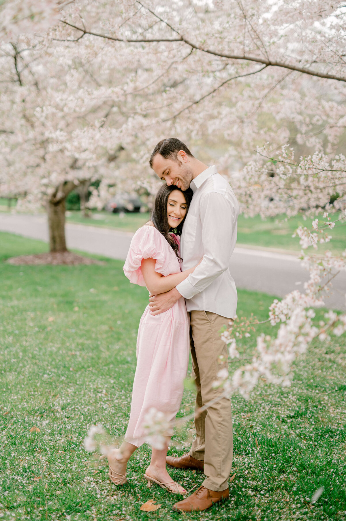 Couple surrounded by  Virginia cherry blossoms for wedding engagement photos