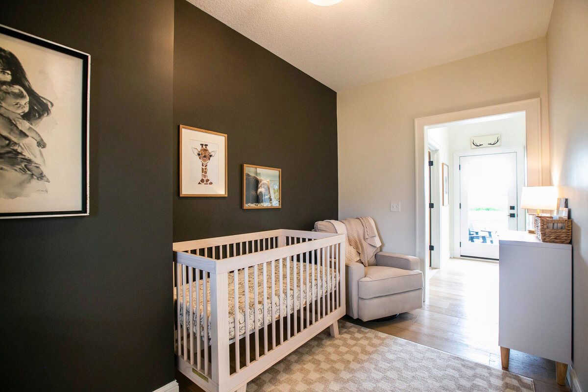 Custom nursery nook in Otsego home with dark walls, wood floors and modern accents designed by Cornerstone Custom Builds