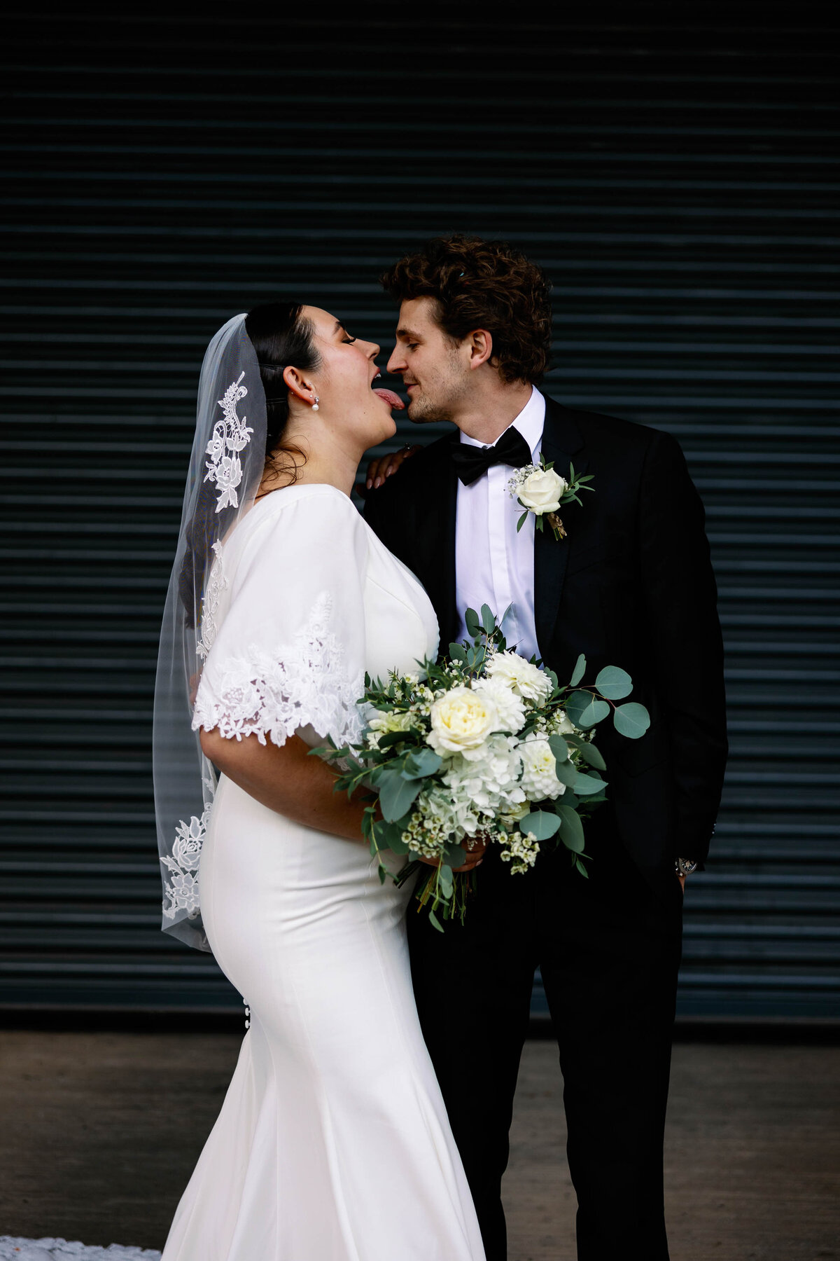 Candid photo of a bride trying to lick the grooms face during portrait session