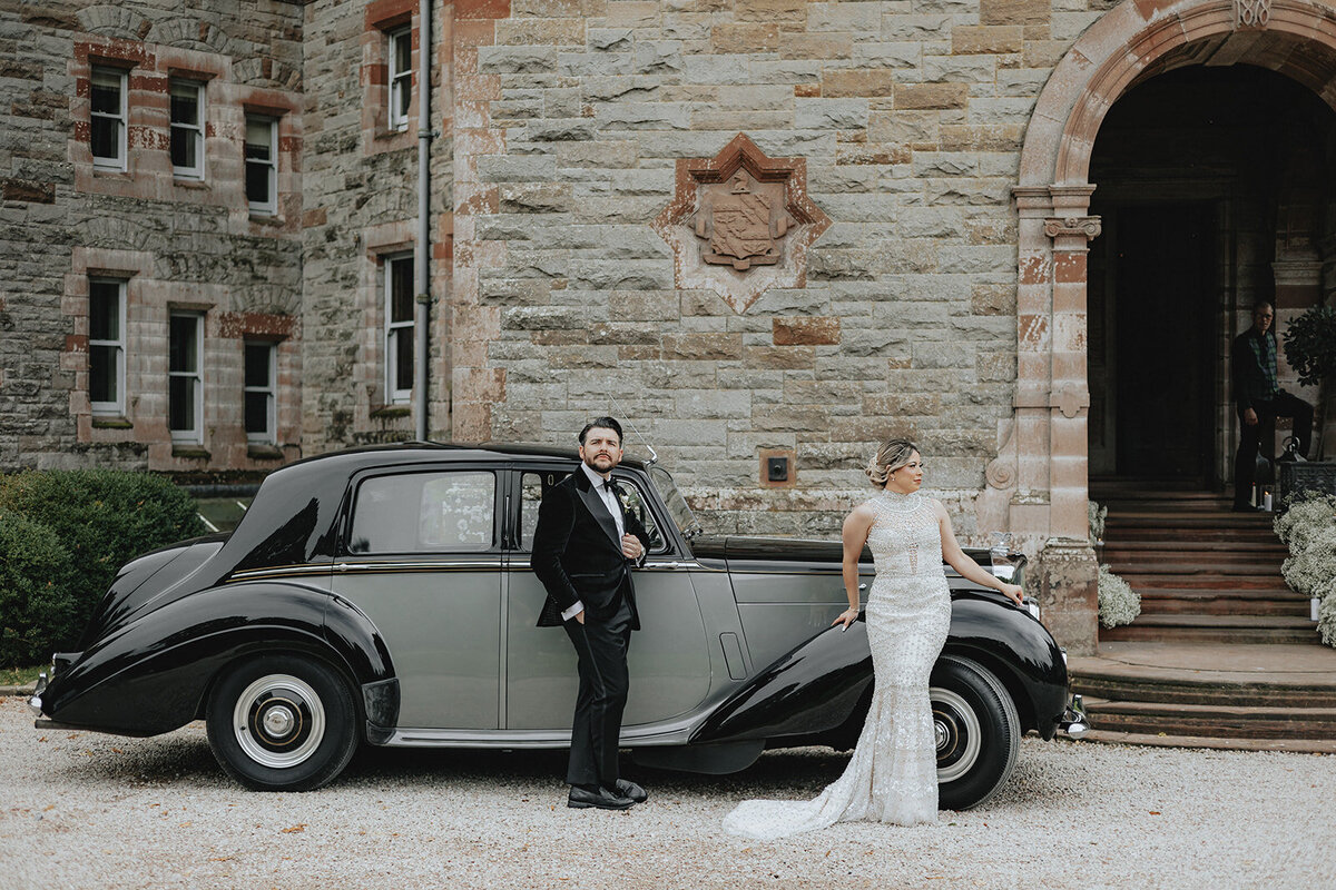 Bride and groom leaning against old car in Ireland