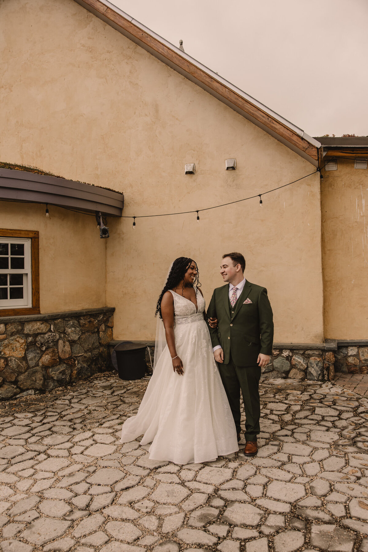 Newlyweds holding hands and standing on a stone patio 