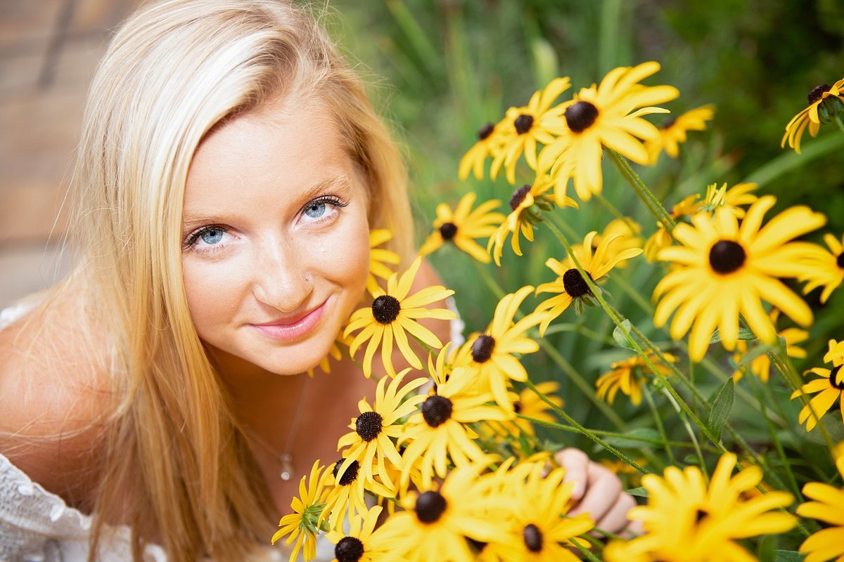 High school senior girl kneeling beside Black-eyed Susan flowers