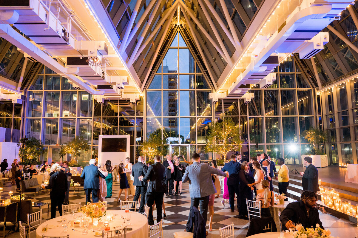 night photo of the inside of wintergarden ppg place wedding reception dance floor lots of colored lights and glass walls