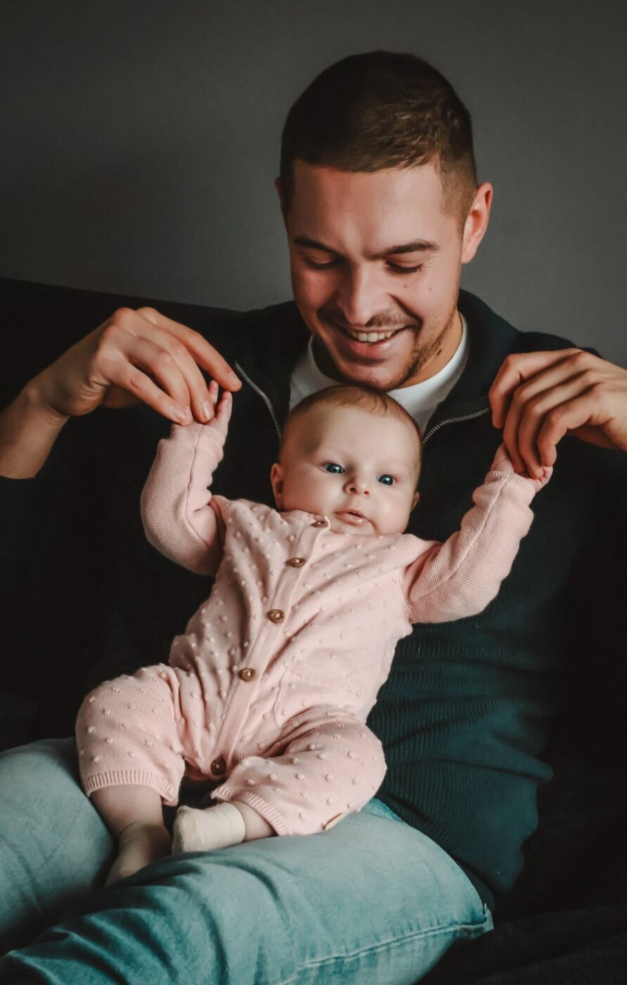 Een vader houdt zijn baby vast, met de nadruk op hun interactie en de tedere blik van de vader.