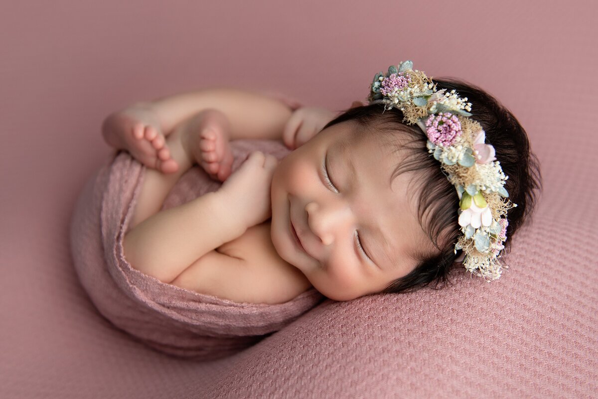 Best newborn photographer West Palm Beach  captures smile of newborn baby girl in a flower crown.