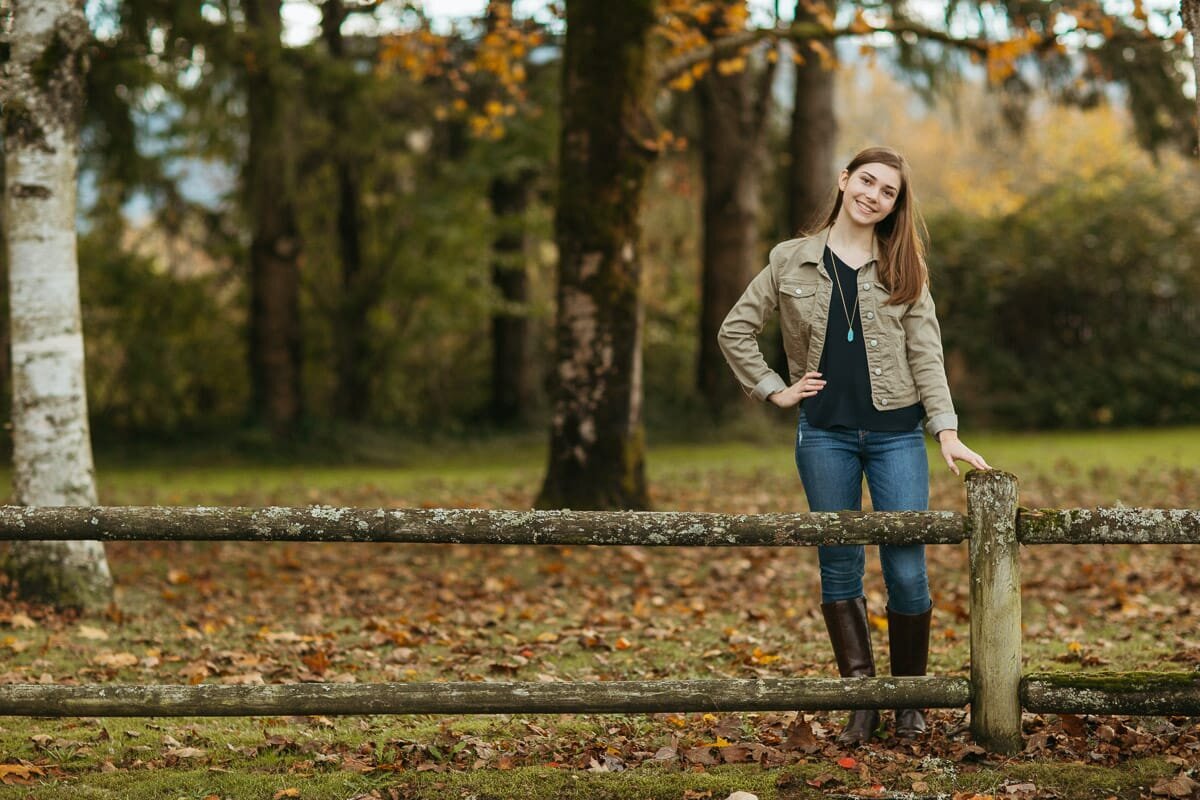 High school senior female standing behind a short fence at an Issaquah Park.
