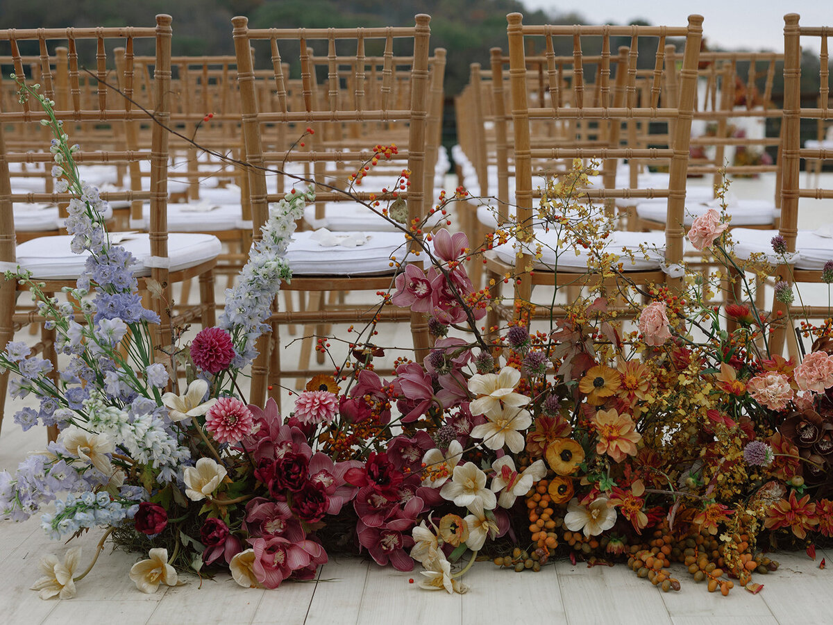 Product clustered floral meadows for entrance to wedding ceremony aisle. Unique fall wedding colors in copper, ruby, lavender, and gold. Artistic and sculptural floral design for fall wedding in Tennessee hills. Flowers featuring ranunculus, orchids, tulips, and dahlias. Custom build platform for private property wedding ceremony. Private home wedding ceremony and reception. Design by Rosemary & Finch Floral Design in Nashville, TN.