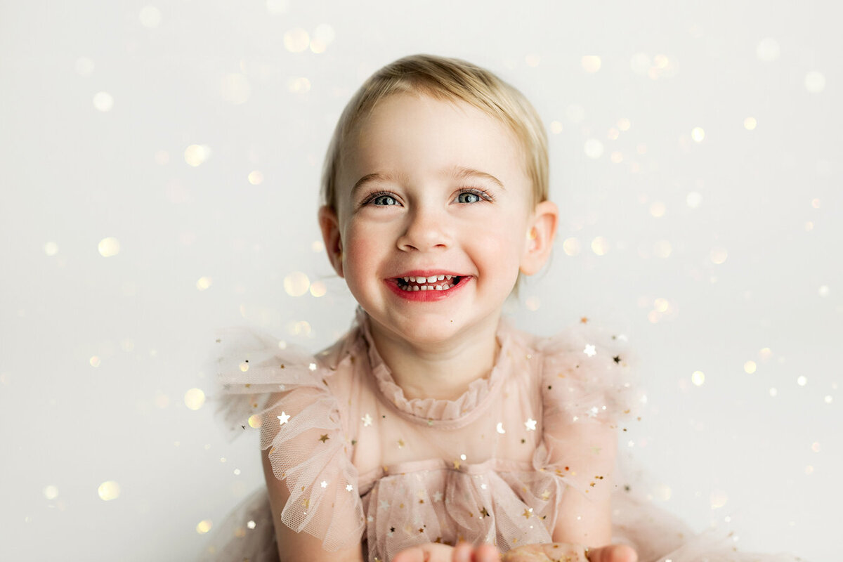 Cute little girl sitting in a sparkly dress smiling