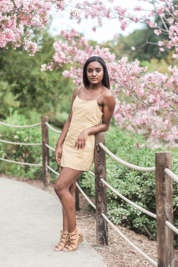 Senior girl leaning against post with pink flowers