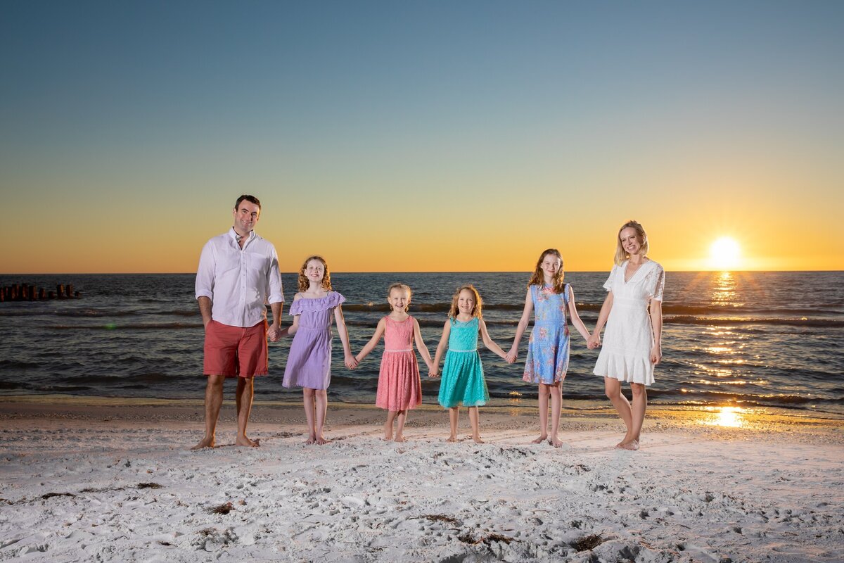 Family holding hands at sunset on the beach taken by Anna Maria Island  family Photographer