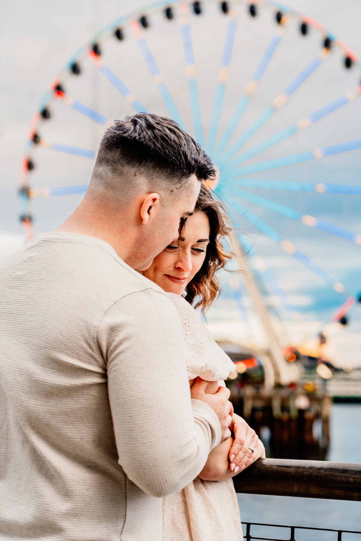 a couple standing in front of the Seattle waterfront ferris wheel next to Pike Place Market