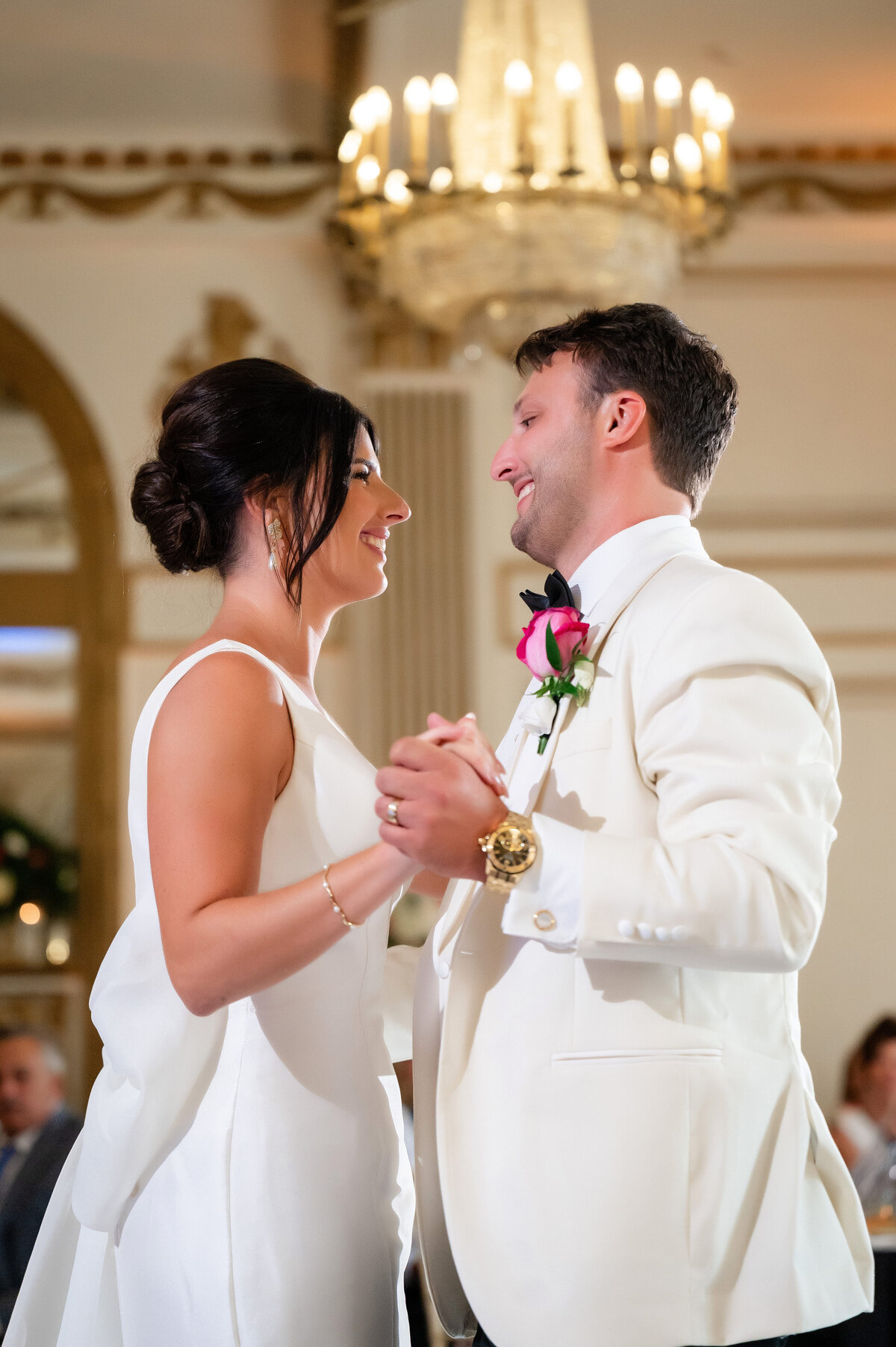 couple both dressed in white smiling at each other while they have their first dance on wedding day