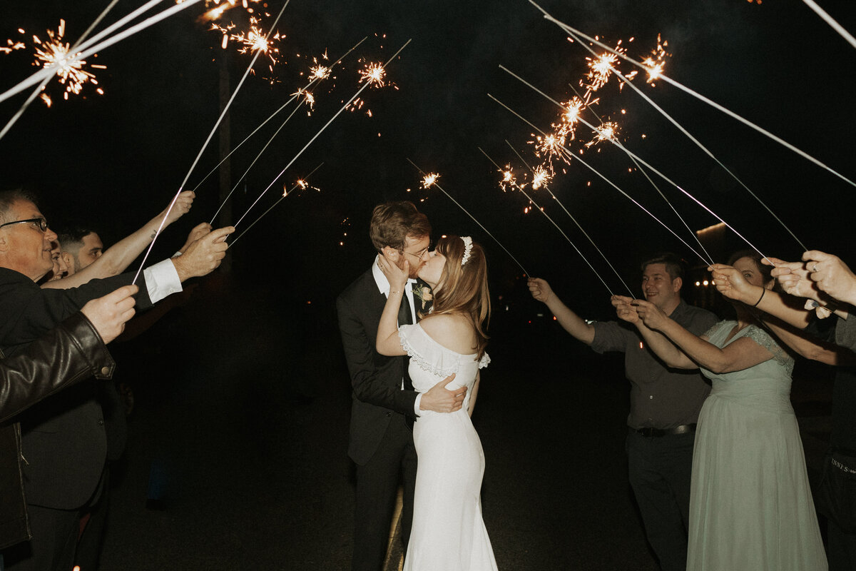 Bride and groom kissing with sparklers around them