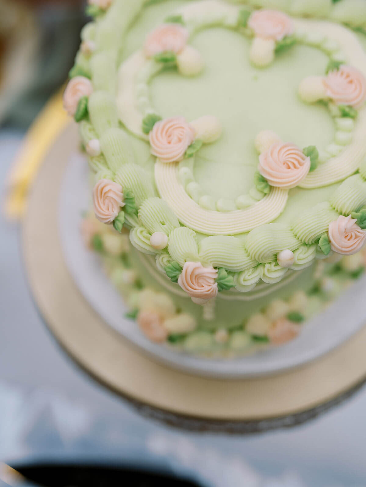 A wedding cake with green frosting and pale pink flowers. 