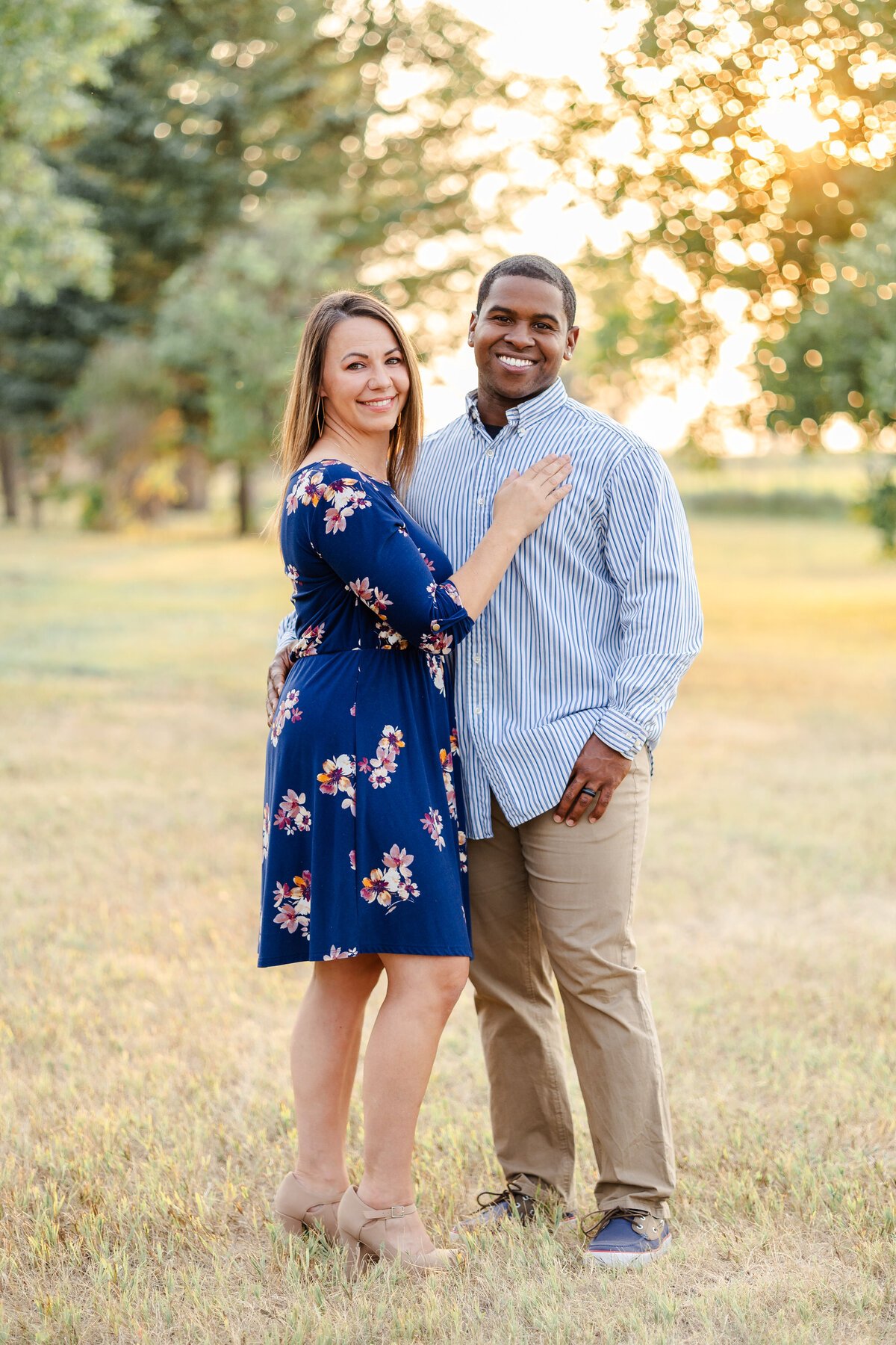 Colorado Springs Photographer - Couple standing in field with glowing sun behind them