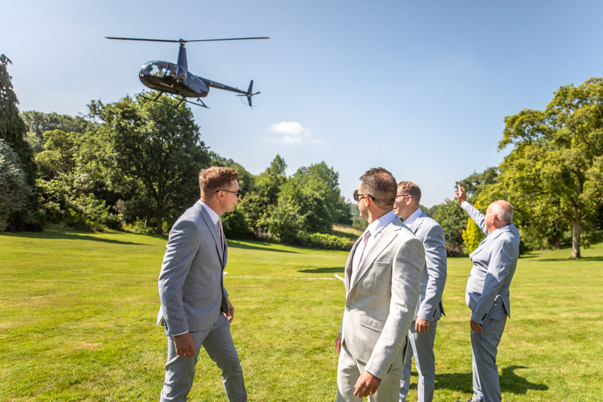 Groomsmen in field with helicopter