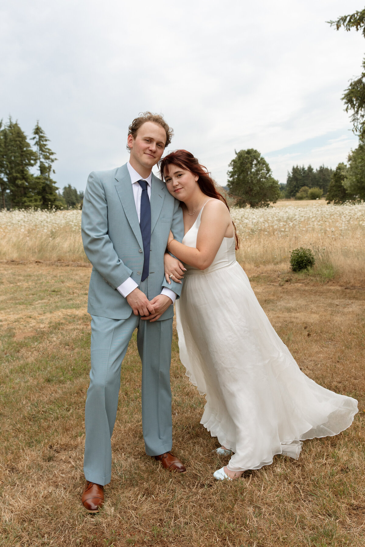 Husband and wife embrace in a field on their wedding day