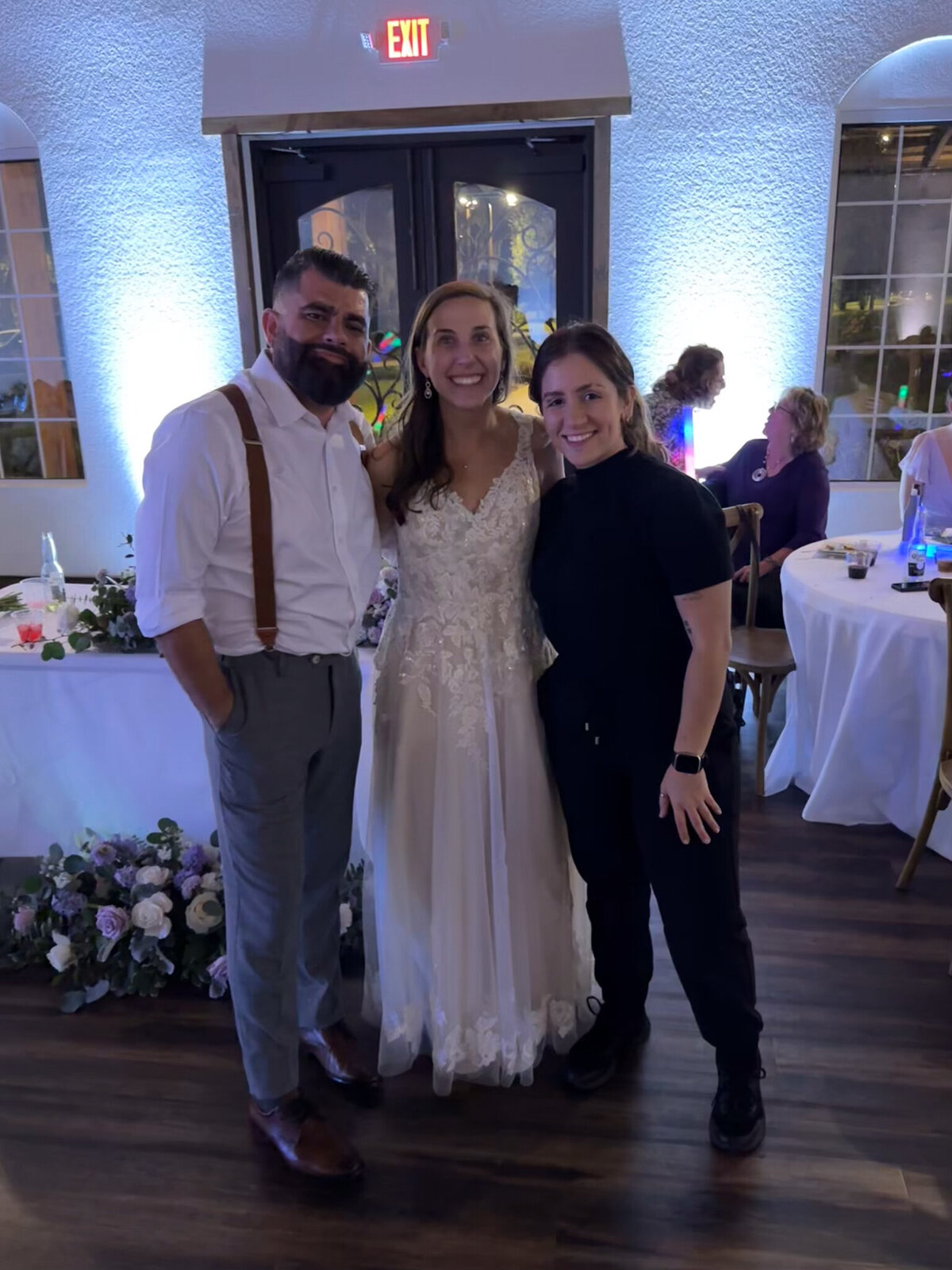 Female wedding photographer posing with newlyweds at Sterling Event Venue in Minneola, Florida, during their reception.