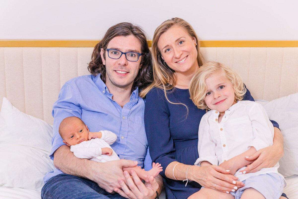 newborn with parent and toddle sibling sitting on a sofa durin in house newborn and family photo session Laure Photography Atlanta family and newborn photographer