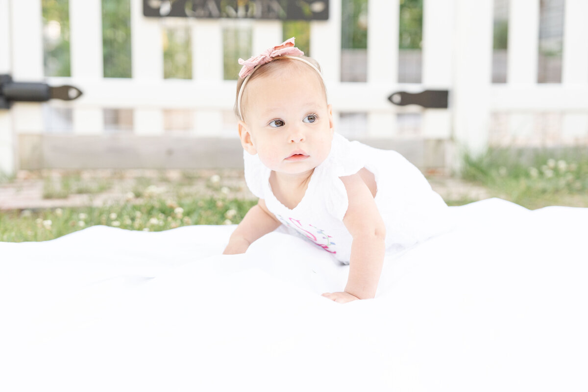 Newborn stretching  her arms and wearing a flower headband.