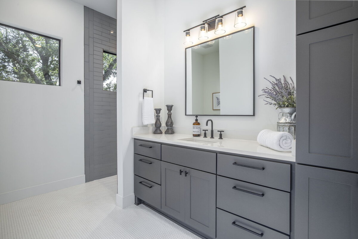 bathroom with gray cabinets, white countertops and white tile flooring